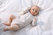 © New Africa - Cute little baby with toy lying on white sheets, top view
