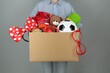 © New Africa - Woman holding box of unwanted stuff on grey background, closeup