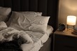 © New Africa - Nightlight, alarm clock, glasses and books on bedside table near bed indoors