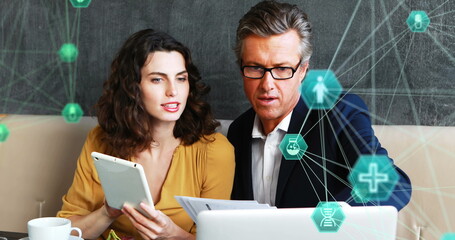 Poster - Caucasian male executive and female colleague analyze data on a tablet