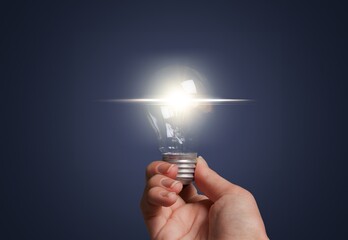 Canvas Print - Business person holding bright light bulb.