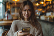 © Anek - A woman is sitting in a cafe and is holding a cell phone