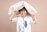 Fototapeta  - Kid Boy in Pajamas Holding Pillow Above The Head Against Beige Background