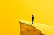 A man in a suit stands on the edge of a yellow cliff, representing decision-making and risk in a minimalistic style