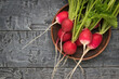 Large fresh radishes in a clay bowl on a wooden table.