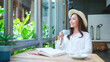 © Farknot Architect - Portrait image of a beautiful young woman with hat drinking coffee while reading book