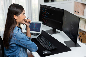 Wall Mural - Young Asian IT developer looking online information on pc for beautiful pose with coding program data of website application, wearing jeans shirt. surround by safety analysis two screens. Stratagem.