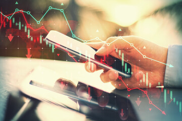 Poster - Side view of male hands using tablet and cellphone at desk with falling red forex chart and map on blurry outdoor background. Trade and crisis concept. Double exposure.
