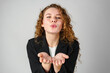 Young Woman Blowing a Kiss Towards the Camera in a Studio Setting