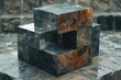 Abstract art in the form of unevenly stacked black cubes with a textural contrast against the stone ground and neutral backdrop