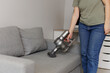woman cleaning sofa with vacuum cleaner