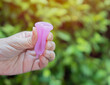 Close-up of young woman hands folding a pink menstrual cup and showing how to use, c form