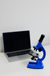 Computer with black screen and blue microscope on white table