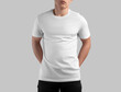 White t-shirt template on guy in dark jeans with hands behind back, front view, isolated on background.