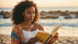 © Firnthirith - A young black woman is reading a book on the beach