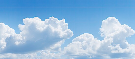 Poster - The serene light blue sky is adorned with fluffy clouds creating a picturesque natural backdrop There is ample copy space in the image