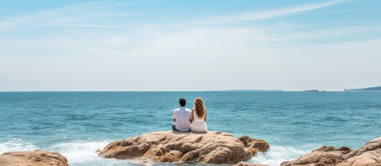 Aufkleber - A couple sitting on a rock by the sea enjoying togetherness during the weekend Copy space image