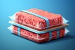 Two packages of fresh raw minced meat on blue background.