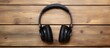 © vxnaghiyev - There is a top view of wireless Black headphones placed on a wooden table with a background that has copy space for images or text