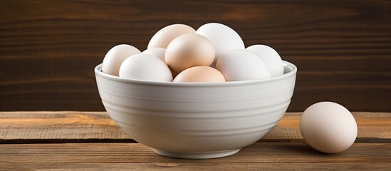 Aufkleber - A closeup image of white eggs in a bowl set against a wooden background with ample copy space