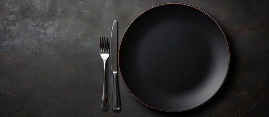 Aufkleber - A moody copy space image capturing a close up view of a cutlery set consisting of an empty plate and a fork placed together on a black table This food concept photography evokes the essence of a sere