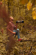 Man using binoculars and camera for bird and animal watching in nature.