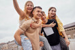© Dasha Petrenko - Cute girls in casual clothes ride on the backs of handsome guys on the roof of the house