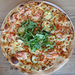 Pizza with arugula, zucchini, mini tomatoes, cheese and salmon