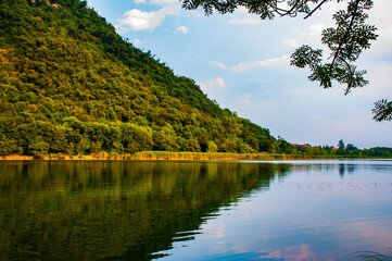 Segrino lake during a sunny day in summer with mountain's reflection on water