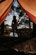 Camping. View from the tent. The silhouette of a young woman standing at the edge of a cliff against the background of trees and water. Outdoor recreation.