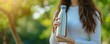 © iSomboon - A woman holds a stainless steel water bottle, suggesting themes of sustainability and eco-friendliness, suitable for Earth Day or environmental campaigns.