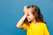 Frustrated beautiful caucasian little girl wearing yellow T-shirt over blue background holding hand on forehead being depressed regretting what he did having headache, looking stressful.