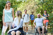 © Robert Kneschke - Group of friends enjoying a sunny day outdoor walk, including persons using wheelchairs and a woman with a prosthetic leg