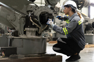 Industrial engineer working on robot maintenance in AI futuristic electronic technology factory. Female technician checking automated robotic machine. Modern smart woman empowerment in industry 4.0.