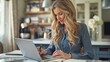 © Multiverse - A woman seated at a kitchen table, focused on working on a laptop