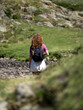 Woman Hiking Through Rocky Mountain Terrain with Backpack and reusable water bottle