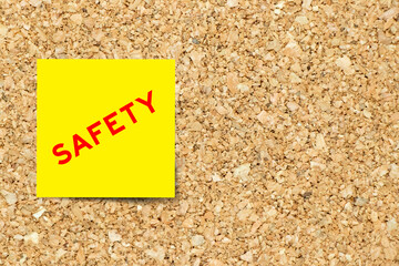 Sticker - Yellow note paper with word safety on cork board background with copy space