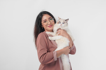 Wall Mural - Lovely Asian woman wearing eyeglasses holding her ragdoll cat and smiling to the camera isolated over white background.