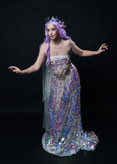 Sticker - Full length portrait of beautiful female model with long purple hair wearing elf ears, a fantasy fairy crown and  rainbow glitter sequin ball gown. graceful standing pose,  isolated in dark studio bac