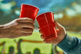 Fototapeta Sport - People clinking red mugs with beer at football stadium during match. Celebrating successful game. Concept of game, leisure, championship, tournament, emotions