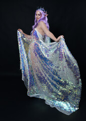 Sticker - Full length portrait of beautiful female model with long purple hair wearing elf ears, a fantasy fairy crown and  rainbow glitter sequin ball gown.  walking away, back view, isolated dark studio 