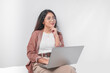 © Reezky - Thoughtful young Asian business woman sitting down with a laptop thinking about work, isolated by white background.