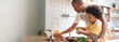 © eggeeggjiew - African American Little boy preparing food while his father looking on the digital recipe and using touch screen tablet in the kitchen at home
