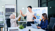© Phushutter - During a dynamic presentation, diverse professionals engage in teamwork, celebrating success with high fives, while discussing financial strategies illustrated on a whiteboard.