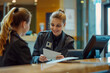 © Kinza - Smiling and beautiful receptionist behind the counter attend the guest standing at the reception desk in a modern hotel