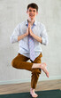 Young guy office worker doing yoga in studio
