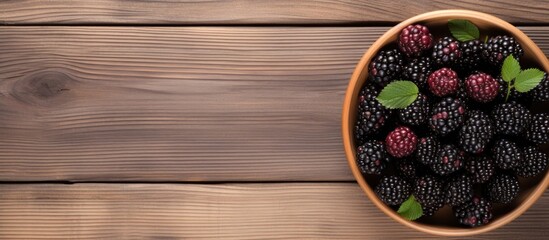Wall Mural - A healthy and vegan coconut bowl filled with fresh and ripe blackberries sits on a wooden background in a top down view offering a copy space image