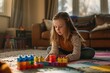 © Jorge Ferreiro - Girl playing with toy blocks sitting at home