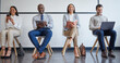 © peopleimages.com - Recruiting, technology and business people in waiting room for hiring process, career opportunity and writing notes. Queue, happy men and women in lobby for job interview with networking and notebook