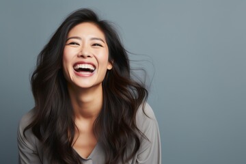 Wall Mural - Portrait of a jovial asian woman in her 30s laughing in front of pastel gray background